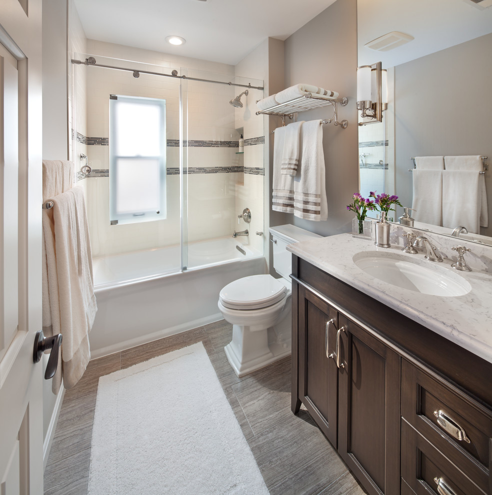 This is an example of a medium sized traditional bathroom in DC Metro with a submerged sink, recessed-panel cabinets, dark wood cabinets, a shower/bath combination, grey tiles, ceramic tiles, grey walls and ceramic flooring.