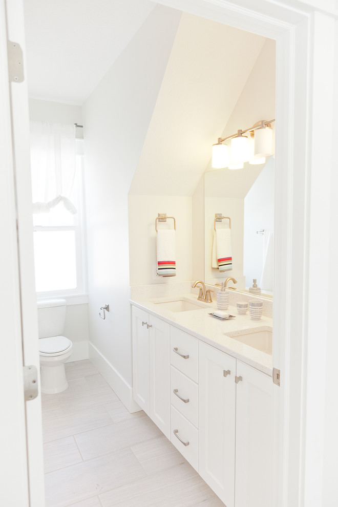 Cette image montre une salle de bain marine de taille moyenne avec un placard à porte shaker, des portes de placard blanches, WC séparés, un mur blanc, un sol en carrelage de porcelaine, un lavabo encastré, un plan de toilette en quartz et un sol beige.