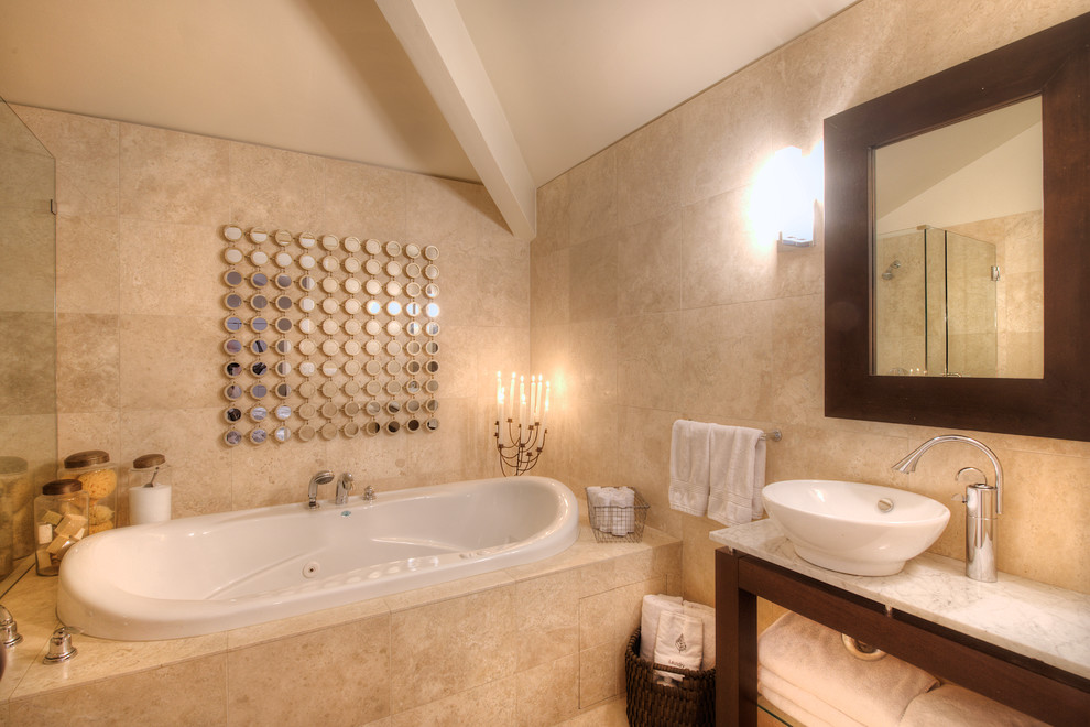 Klassisk inredning av ett mellanstort en-suite badrum, med ett fristående handfat, öppna hyllor, skåp i mörkt trä, marmorbänkskiva, ett badkar i en alkov, beige kakel, porslinskakel, beige väggar och klinkergolv i porslin