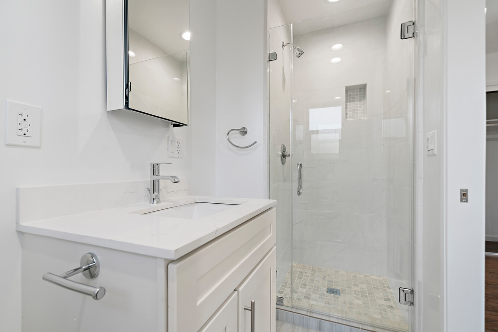 Foto på ett litet funkis vit badrum med dusch, med skåp i shakerstil, vita skåp, en hörndusch, en toalettstol med hel cisternkåpa, vit kakel, vita väggar, ett undermonterad handfat, bänkskiva i kvarts och dusch med gångjärnsdörr