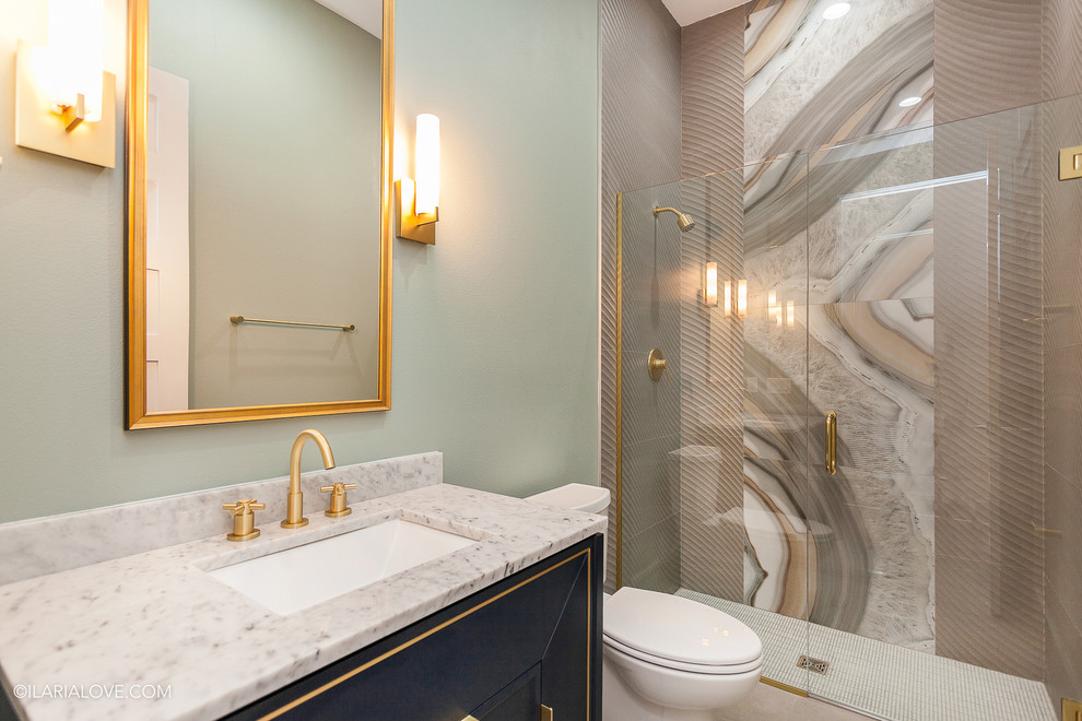 Inredning av ett modernt mellanstort en-suite badrum, med blå skåp, ett undermonterad handfat, dusch med gångjärnsdörr, luckor med infälld panel, en kantlös dusch, en toalettstol med hel cisternkåpa, brun kakel, marmorkakel, bruna väggar, marmorbänkskiva, kalkstensgolv och beiget golv