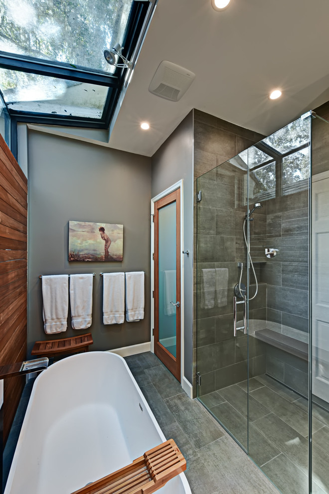Inspiration for a large contemporary ensuite bathroom in Phoenix with flat-panel cabinets, medium wood cabinets, a freestanding bath, a corner shower, grey tiles, ceramic tiles, grey walls, ceramic flooring, an integrated sink and solid surface worktops.
