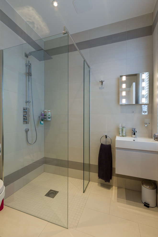 Foto på ett stort funkis en-suite badrum, med ett väggmonterat handfat, öppna hyllor, vita skåp, en kantlös dusch, beige kakel, beige väggar och klinkergolv i keramik