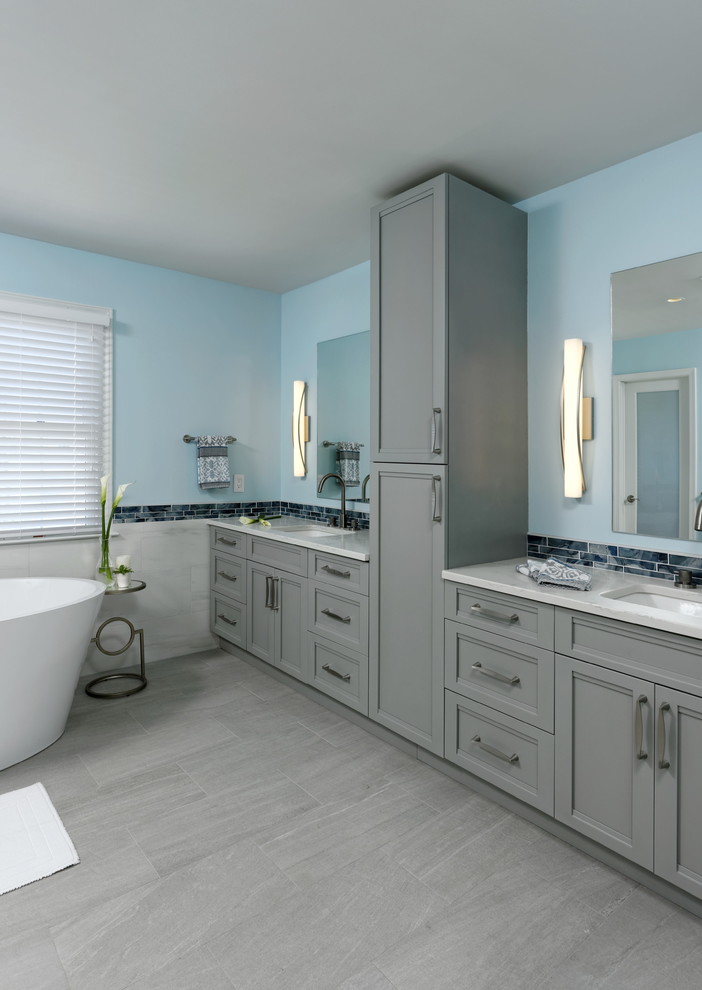 Bathroom - large transitional master white tile and marble tile porcelain tile and gray floor bathroom idea in DC Metro with recessed-panel cabinets, gray cabinets, a two-piece toilet, blue walls, an undermount sink, quartzite countertops, a hinged shower door and white countertops