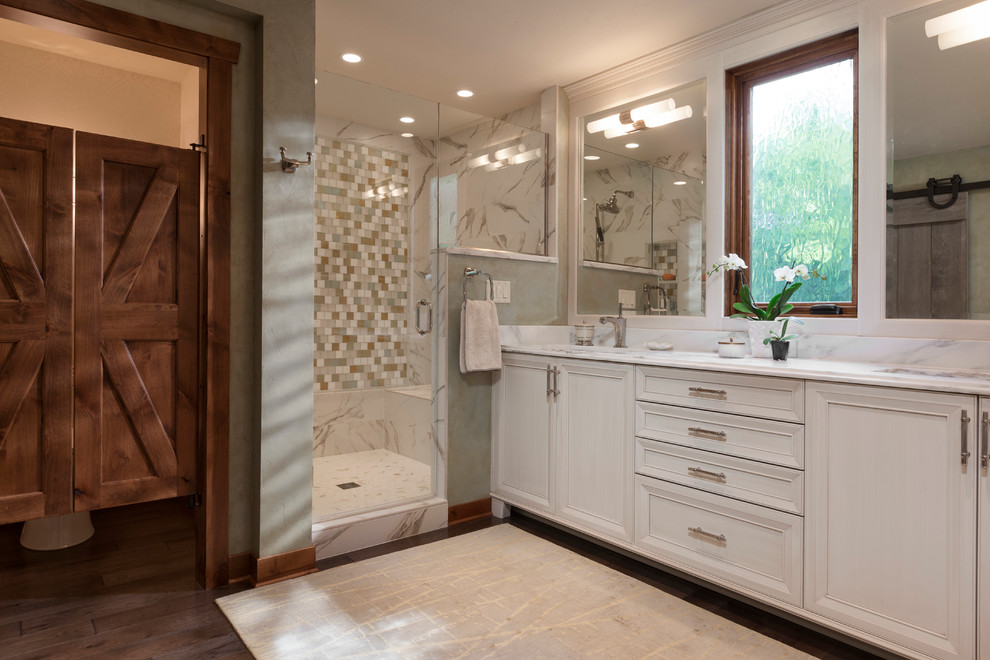 Design ideas for a large rustic ensuite bathroom in Milwaukee with recessed-panel cabinets, white cabinets, an alcove shower, a two-piece toilet, beige tiles, mosaic tiles, beige walls, dark hardwood flooring, a submerged sink, brown floors, a hinged door and multi-coloured worktops.
