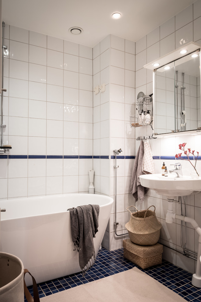 Idéer för att renovera ett nordiskt badrum, med ett fristående badkar, vit kakel, ett väggmonterat handfat och blått golv