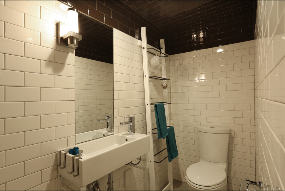 Immagine di una piccola stanza da bagno con doccia minimal con lavabo sospeso, doccia aperta, WC monopezzo, piastrelle bianche, piastrelle in ceramica, pareti bianche e pavimento in cemento