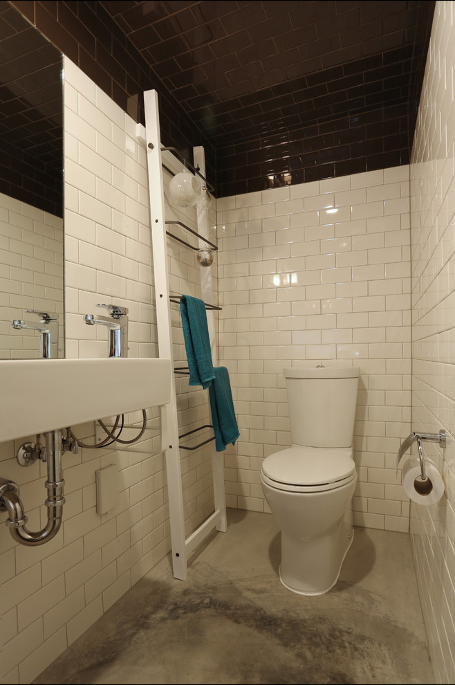 Ispirazione per una piccola stanza da bagno con doccia design con lavabo sospeso, doccia aperta, WC monopezzo, piastrelle bianche, piastrelle in ceramica, pareti bianche e pavimento in cemento