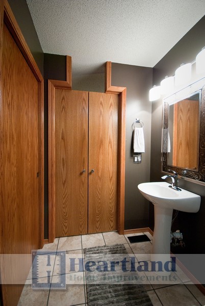 Modelo de cuarto de baño principal clásico renovado de tamaño medio con puertas de armario de madera clara, paredes marrones, lavabo con pedestal y suelo beige
