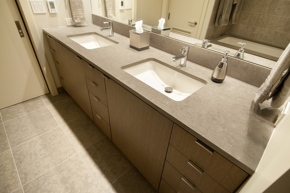 Example of a large trendy master gray tile and stone slab limestone floor and gray floor bathroom design in Seattle with flat-panel cabinets, white walls, an undermount sink, solid surface countertops, medium tone wood cabinets, a bidet and a hinged shower door
