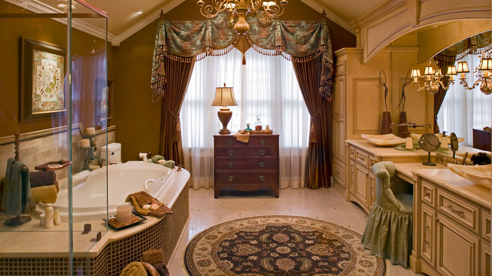 Diseño de cuarto de baño principal clásico con lavabo sobreencimera, armarios tipo mueble, puertas de armario beige, encimera de mármol, baldosas y/o azulejos beige y paredes marrones