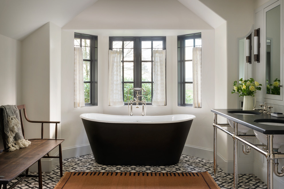 Diseño de cuarto de baño mediterráneo con bañera exenta, paredes blancas, lavabo bajoencimera, suelo multicolor y encimeras negras