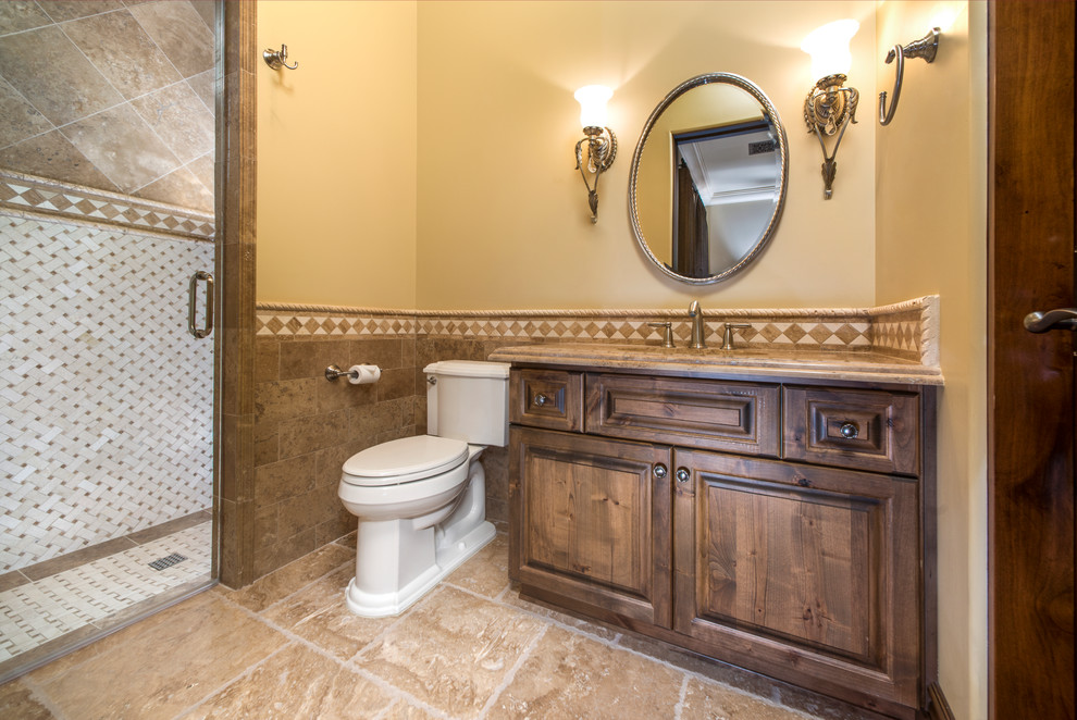 Expansive traditional shower room bathroom in Phoenix with flat-panel cabinets, medium wood cabinets, a built-in shower, a two-piece toilet, beige tiles, mosaic tiles, black walls, travertine flooring, a built-in sink and granite worktops.