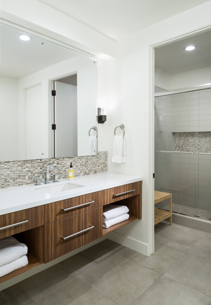 Réalisation d'une très grande salle de bain design en bois brun avec un placard à porte plane, une douche d'angle, un carrelage beige, mosaïque, un mur blanc, un lavabo encastré, un sol gris et un plan de toilette blanc.