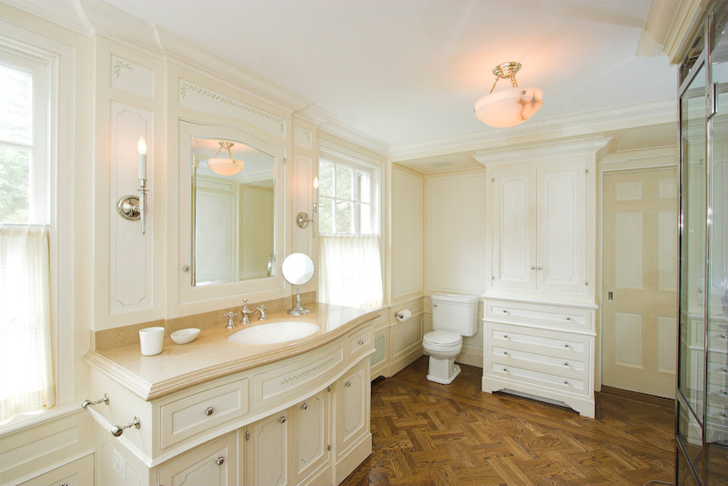 Example of a large classic master medium tone wood floor tub/shower combo design in New York with an undermount sink, furniture-like cabinets, white cabinets, limestone countertops, an undermount tub, a two-piece toilet and white walls