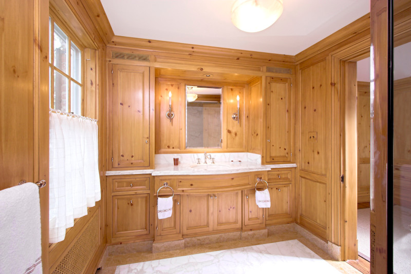 На фото: большая главная ванная комната в классическом стиле с врезной раковиной, фасадами островного типа, светлыми деревянными фасадами, мраморной столешницей, полновстраиваемой ванной, душем над ванной, раздельным унитазом, белыми стенами и мраморным полом