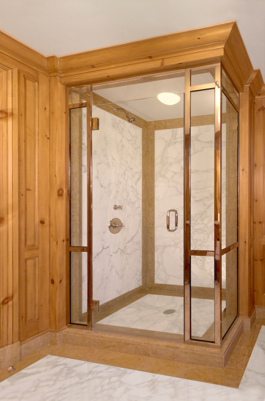 Diseño de cuarto de baño principal tradicional grande con lavabo bajoencimera, armarios tipo mueble, puertas de armario de madera clara, encimera de mármol, bañera encastrada sin remate, sanitario de dos piezas, paredes blancas y suelo de mármol
