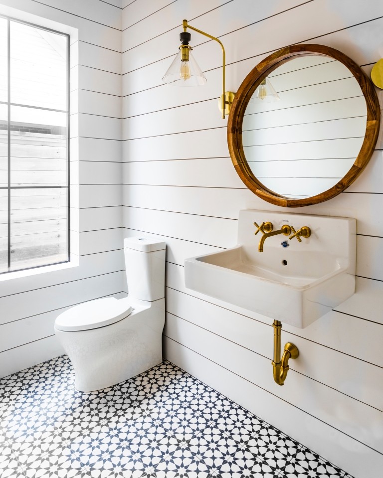Lantlig inredning av ett mellanstort badrum, med cementgolv, svart golv, en toalettstol med separat cisternkåpa, vita väggar och ett väggmonterat handfat