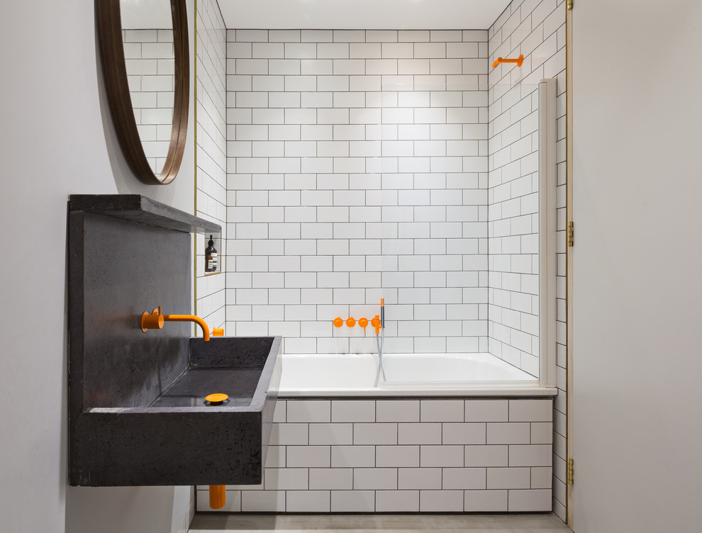 Photo of a medium sized contemporary bathroom in London with a built-in bath, white tiles, metro tiles, grey floors, white walls and a wall-mounted sink.