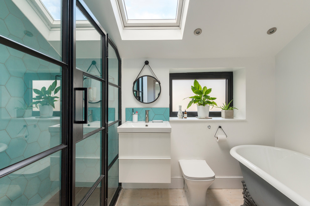 Photo of a small contemporary bathroom in London with flat-panel cabinets, white cabinets, a freestanding bath, a corner shower, a one-piece toilet, blue tiles, white walls, light hardwood flooring, a wall-mounted sink, beige floors and a hinged door.