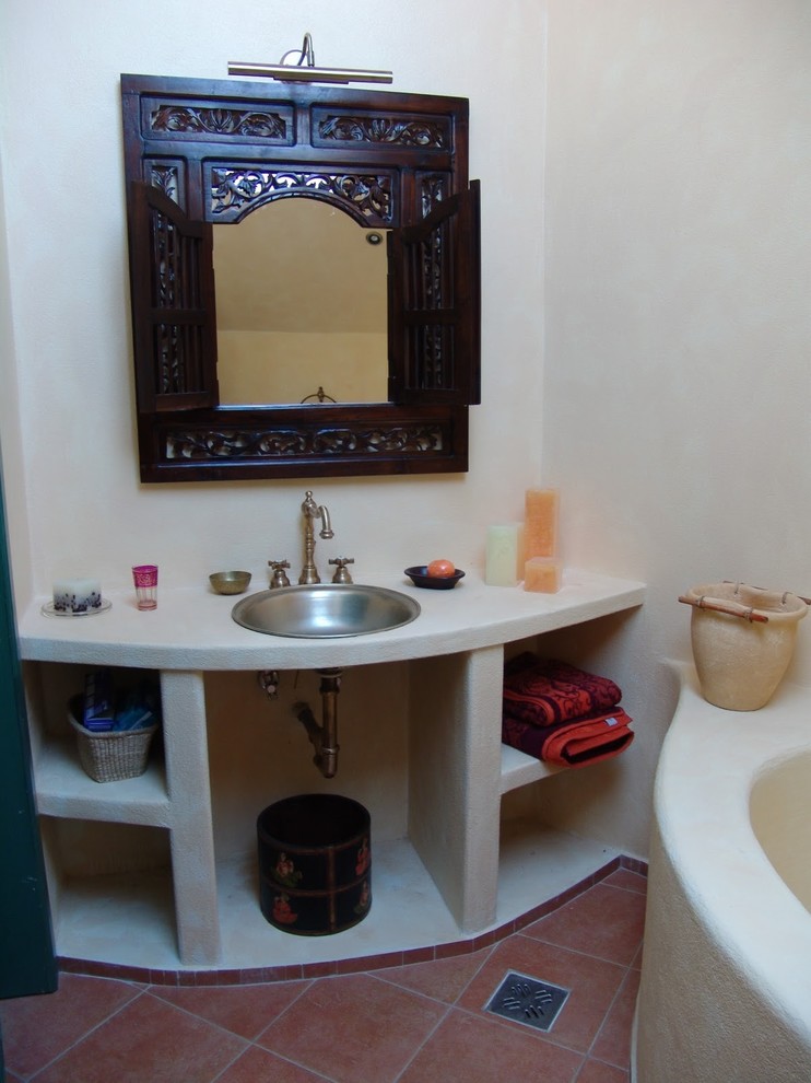 Modelo de cuarto de baño principal de estilo zen con lavabo encastrado, encimera de cemento, bañera encastrada, ducha a ras de suelo, sanitario de una pieza, baldosas y/o azulejos beige, paredes beige y suelo de baldosas de terracota