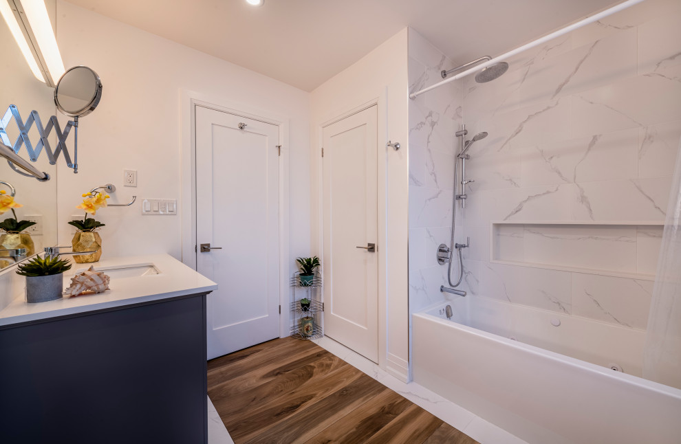 Photo of a medium sized modern ensuite bathroom in Toronto with shaker cabinets, dark wood cabinets, a built-in bath, an alcove shower, a two-piece toilet, blue walls, vinyl flooring, engineered stone worktops, a sliding door, white worktops, a single sink and a freestanding vanity unit.
