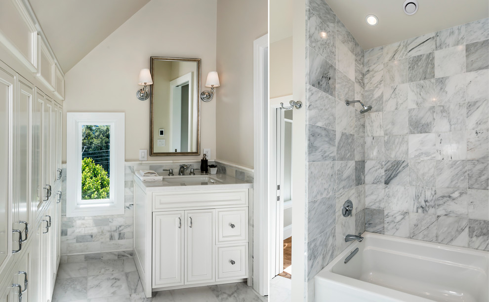 Inredning av ett klassiskt stort badrum för barn, med möbel-liknande, vita skåp, ett undermonterat badkar, en dusch/badkar-kombination, grå kakel, stenkakel, vita väggar, mellanmörkt trägolv, ett undermonterad handfat och marmorbänkskiva