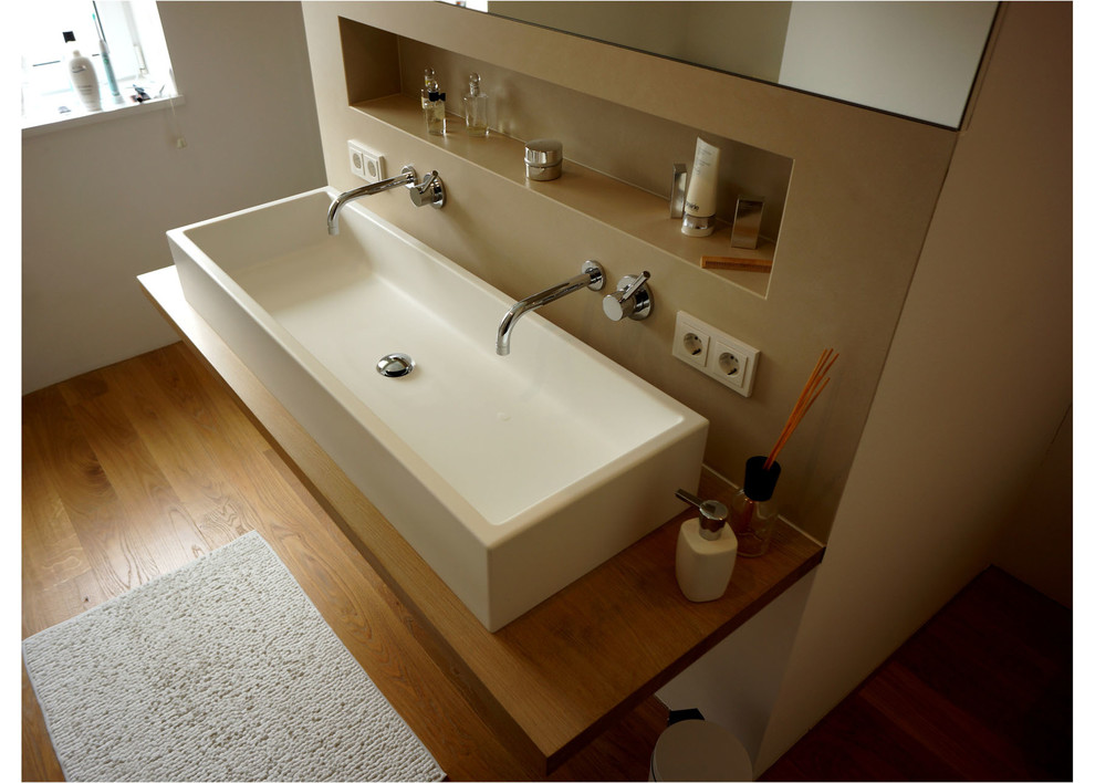 Large modern bathroom in Munich with brown walls, light hardwood flooring, a trough sink and wooden worktops.