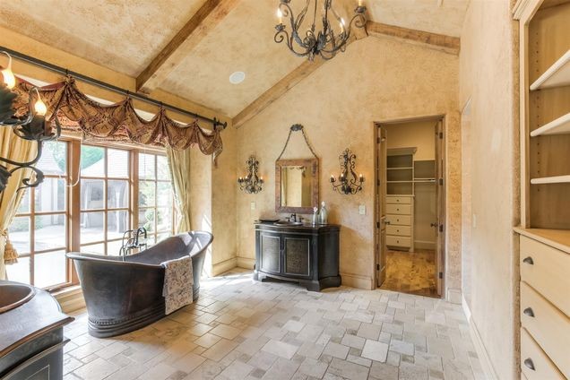 Cette image montre une grande salle de bain principale chalet en bois clair avec un placard sans porte, une baignoire indépendante, un mur beige, un sol en travertin et un lavabo posé.
