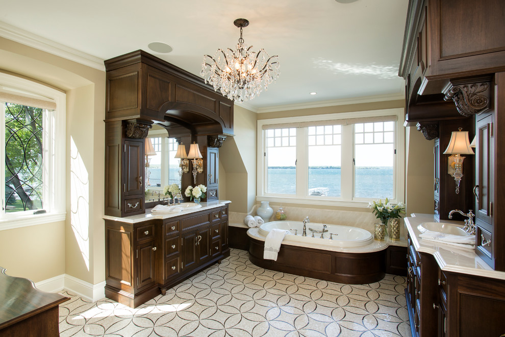 Foto di una stanza da bagno classica con ante con riquadro incassato, ante in legno bruno, vasca da incasso, pareti beige e lavabo da incasso