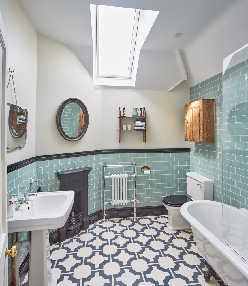 Cette photo montre une salle de bain principale chic avec une baignoire sur pieds, WC séparés, un carrelage bleu, un carrelage métro, un mur blanc, un lavabo de ferme et un sol multicolore.