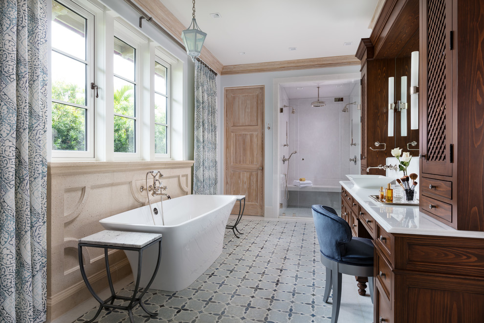 На фото: ванная комната в средиземноморском стиле с фасадами с утопленной филенкой, темными деревянными фасадами, отдельно стоящей ванной, двойным душем, серыми стенами, настольной раковиной, разноцветным полом, душем с распашными дверями и белой столешницей