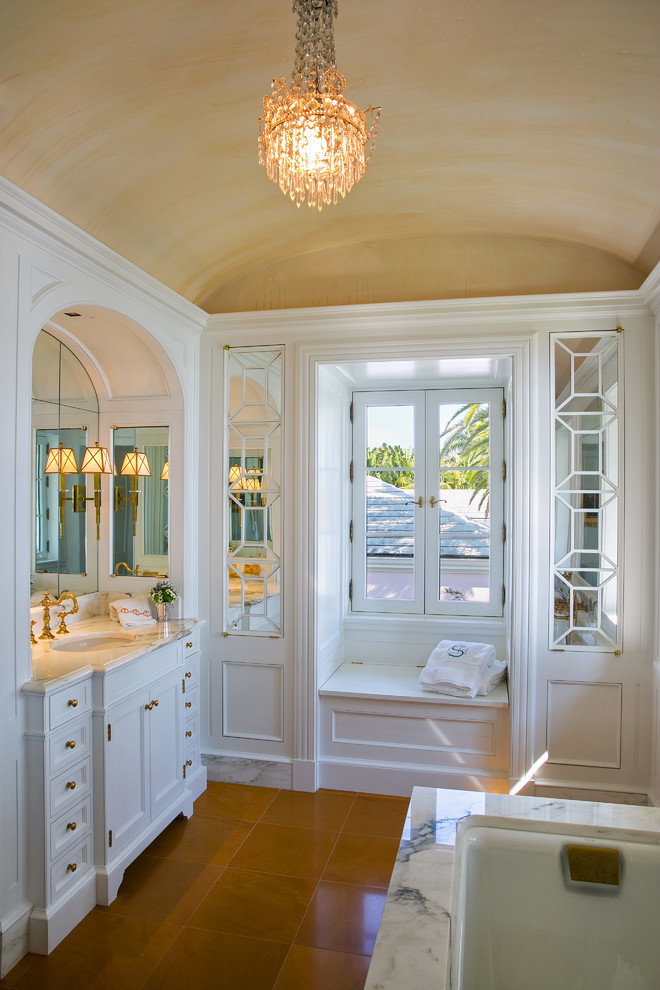 Idée de décoration pour une grande salle de bain principale tradition avec un placard en trompe-l'oeil, des portes de placard blanches, un mur blanc, un sol en carrelage de porcelaine, un lavabo encastré, un plan de toilette en marbre et un sol marron.