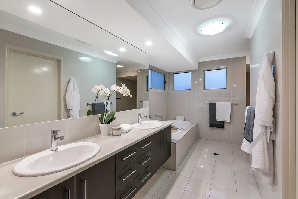 Modelo de cuarto de baño tradicional renovado con armarios con paneles lisos, puertas de armario negras, bañera encastrada, lavabo encastrado, suelo beige y encimeras beige