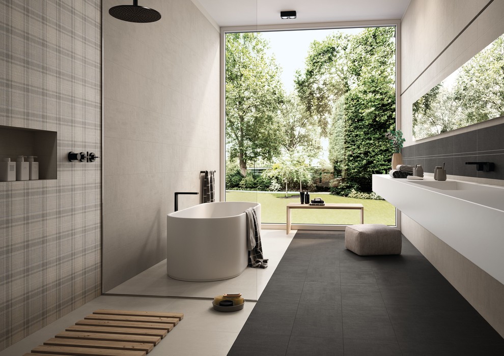 Inredning av ett modernt stort en-suite badrum, med ett fristående badkar, våtrum, grå kakel, cementkakel, grå väggar, betonggolv, ett integrerad handfat, bänkskiva i kvarts, svart golv och med dusch som är öppen