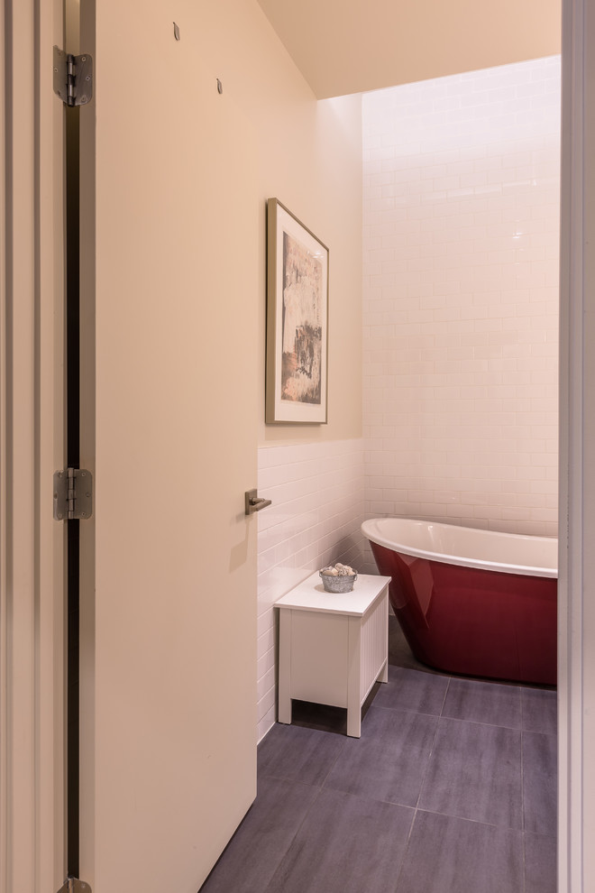 Inspiration pour une salle de bain urbaine avec un placard à porte plane, des portes de placard blanches, une baignoire indépendante, un carrelage blanc, un carrelage métro, un mur blanc, un sol en carrelage de porcelaine, un lavabo intégré et un sol gris.