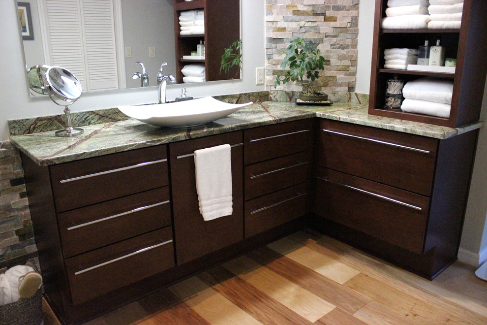 Inspiration for a large world-inspired ensuite bathroom in Tampa with flat-panel cabinets, dark wood cabinets, a freestanding bath, a corner shower, a two-piece toilet, beige tiles, brown tiles, grey tiles, multi-coloured tiles, stone tiles, grey walls, light hardwood flooring, a vessel sink, granite worktops and green worktops.