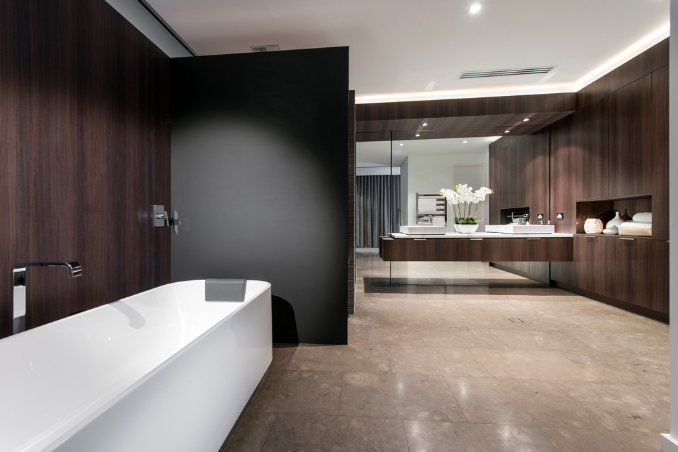 Стильный дизайн: огромная главная ванная комната в современном стиле с настольной раковиной, плоскими фасадами, темными деревянными фасадами, мраморной столешницей, отдельно стоящей ванной, керамической плиткой и полом из известняка - последний тренд