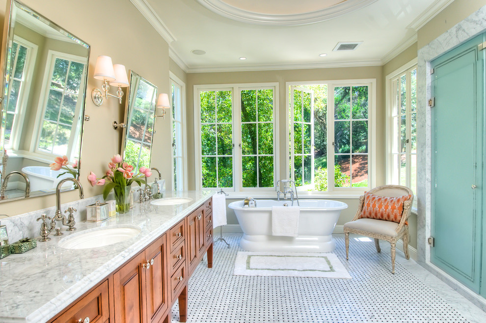 Inredning av ett klassiskt stort en-suite badrum, med ett undermonterad handfat, ett fristående badkar, beige väggar, marmorgolv, luckor med upphöjd panel och skåp i mellenmörkt trä