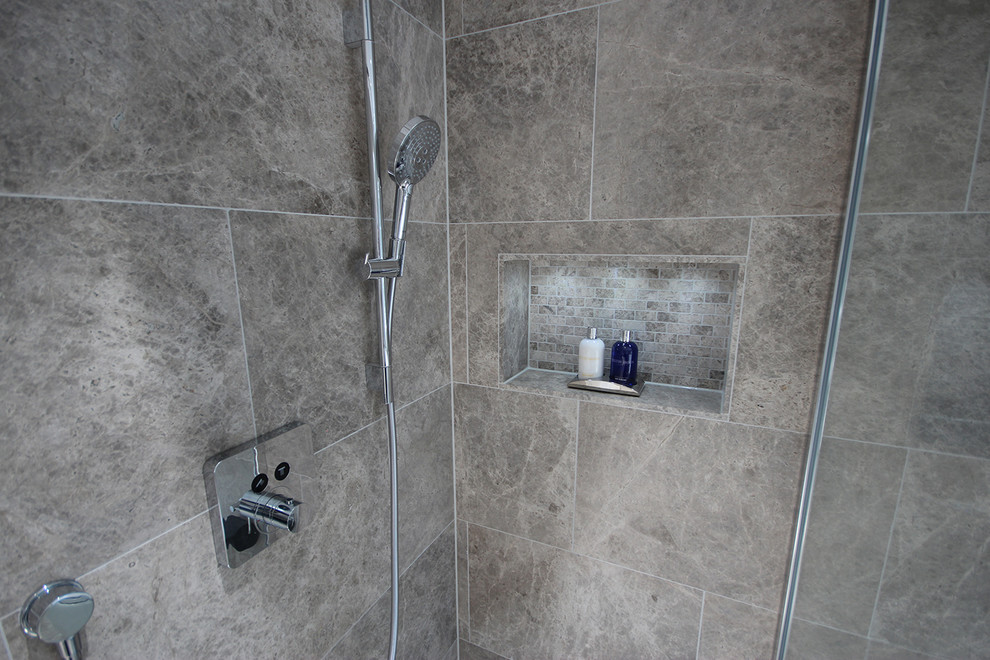 Inspiration för stora moderna en-suite badrum, med släta luckor, grå skåp, ett fristående badkar, våtrum, en vägghängd toalettstol, grå kakel, stenkakel, grå väggar, kalkstensgolv, ett väggmonterat handfat och grått golv