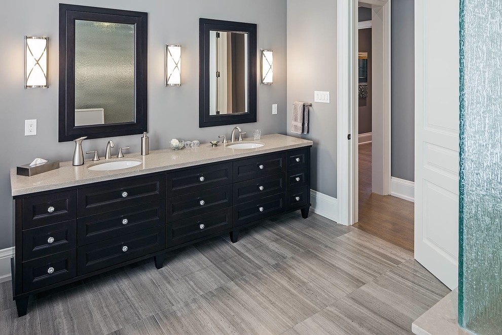 Modelo de cuarto de baño principal clásico renovado grande con lavabo encastrado, armarios con paneles empotrados, puertas de armario negras, encimera de granito, bañera encastrada y paredes grises
