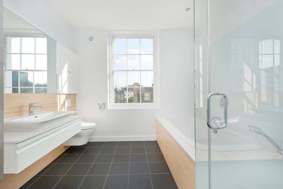 Medium sized contemporary ensuite bathroom in London with a wall-mounted sink, flat-panel cabinets, white cabinets, quartz worktops, a built-in bath, a corner shower, a wall mounted toilet, black tiles, porcelain tiles, white walls and porcelain flooring.