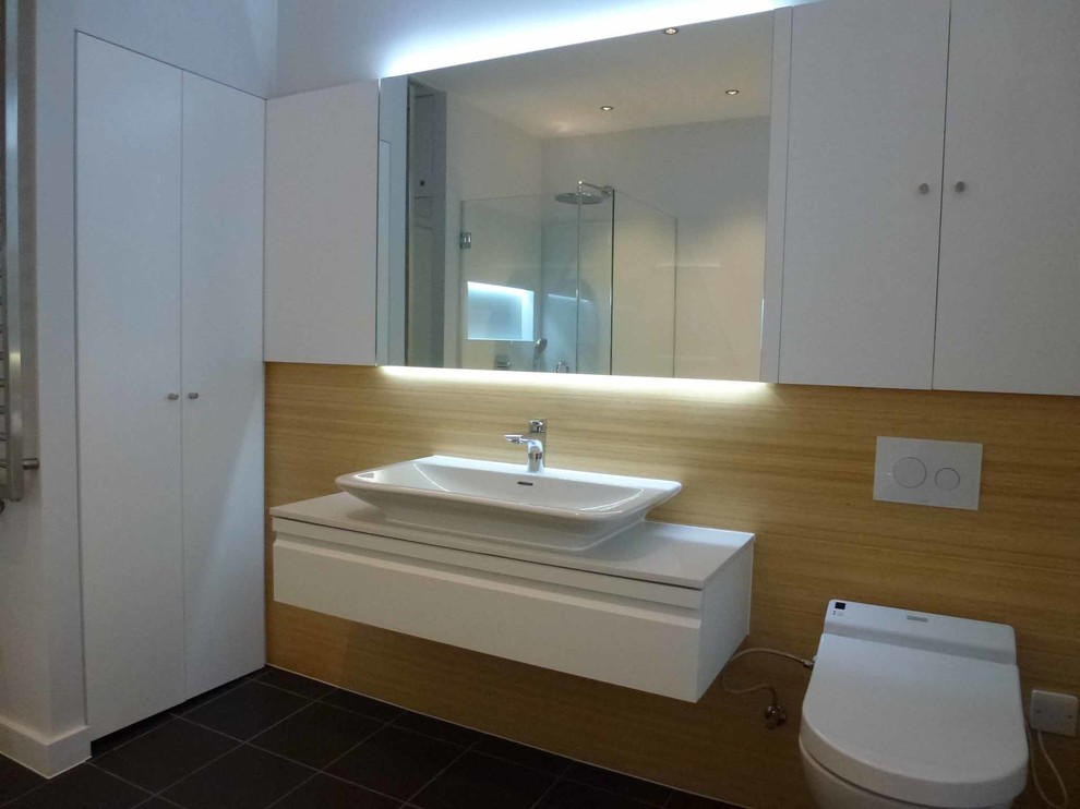 Medium sized contemporary ensuite bathroom in London with flat-panel cabinets, white cabinets, quartz worktops, a wall mounted toilet, black tiles, porcelain tiles and porcelain flooring.