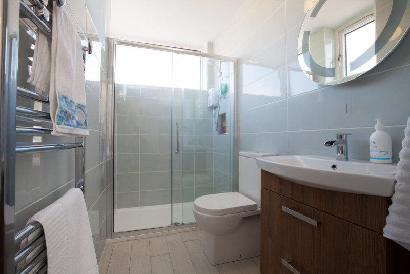 Ispirazione per una stanza da bagno con ante marroni, doccia aperta, WC a due pezzi, piastrelle blu, piastrelle in ceramica, pareti blu e porta doccia scorrevole