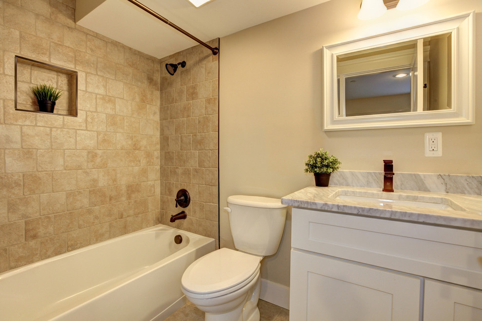 Idéer för att renovera ett amerikanskt badrum, med skåp i shakerstil, beige kakel, keramikplattor, beige väggar, klinkergolv i keramik, ett undermonterad handfat, vita skåp, ett badkar i en alkov, en dusch/badkar-kombination, en toalettstol med separat cisternkåpa och bänkskiva i kvartsit