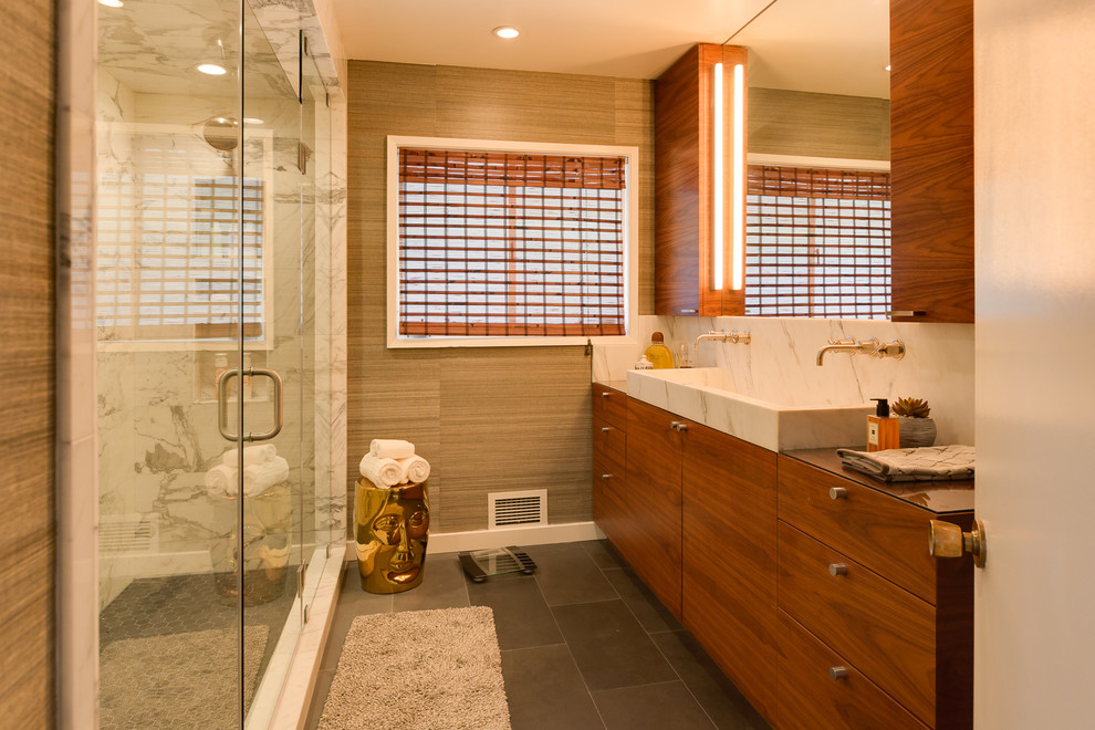 Стильный дизайн: большая главная ванная комната в стиле модернизм с двойным душем, серой плиткой, коричневыми стенами, плоскими фасадами, светлыми деревянными фасадами, раковиной с несколькими смесителями и мраморной столешницей - последний тренд