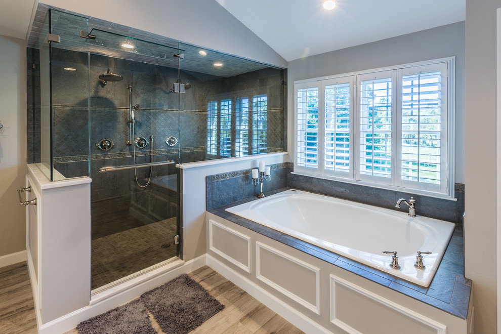 This is an example of an expansive midcentury ensuite bathroom in DC Metro with raised-panel cabinets, grey cabinets, a built-in bath, a double shower, grey tiles, cement tiles, grey walls, medium hardwood flooring, a submerged sink, marble worktops, brown floors, a hinged door and white worktops.