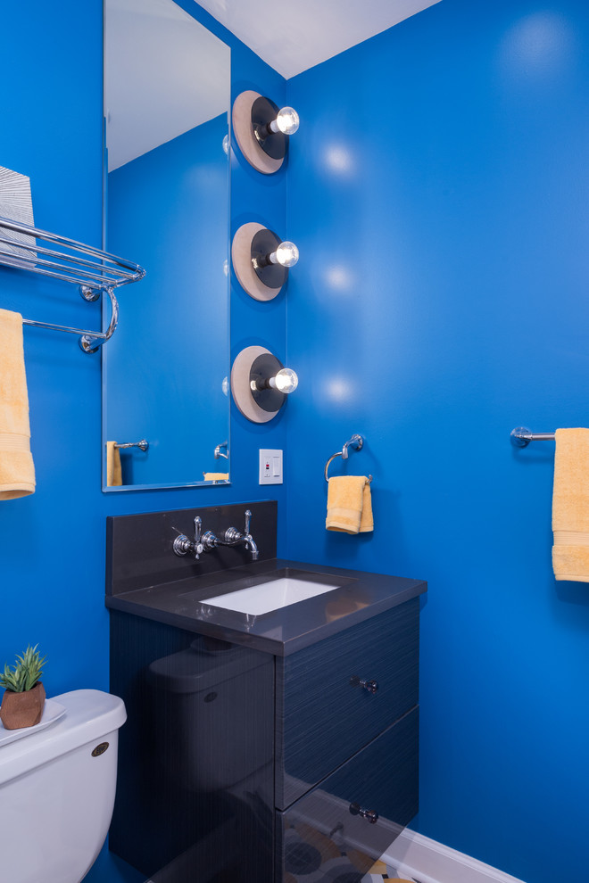 Foto på ett mellanstort eklektiskt en-suite badrum, med släta luckor, svarta skåp, ett platsbyggt badkar, en dusch/badkar-kombination, en toalettstol med hel cisternkåpa, vit kakel, keramikplattor, blå väggar, klinkergolv i keramik, ett undermonterad handfat och bänkskiva i kalksten