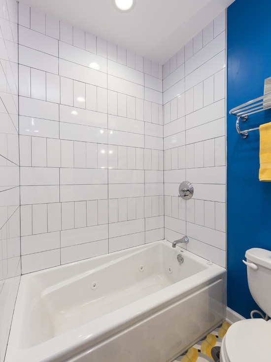 Cette image montre une salle de bain principale bohème en bois brun de taille moyenne avec un placard à porte plane, une baignoire posée, un combiné douche/baignoire, WC à poser, un carrelage blanc, des carreaux de céramique, un mur bleu, un sol en carrelage de céramique, un lavabo encastré et un plan de toilette en calcaire.