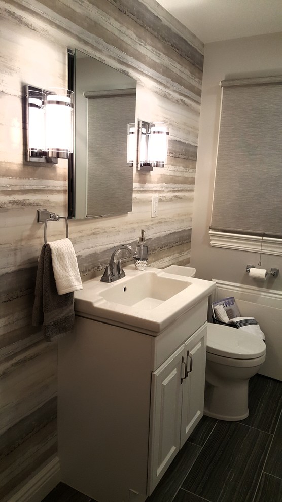 Photo of a medium sized classic bathroom in New York with raised-panel cabinets, white cabinets, an alcove bath, grey tiles, porcelain tiles, grey walls, porcelain flooring, an integrated sink and grey floors.